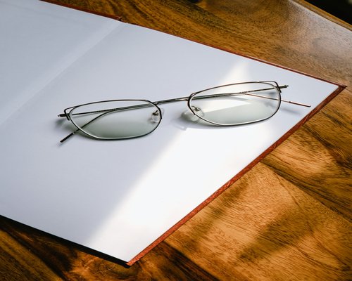 Open book with glasses on a wooden table